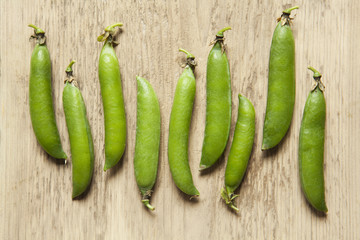 Green pea pods on a wooden background. 
