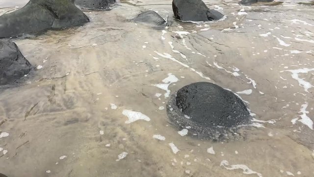 A video of a set os small puddles in the sand on the shore of a beach