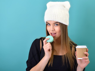 Hipster girl eating french macaron and coffee over turquoise bac