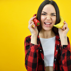 Hipster girl holding near her face banana and chili pepper like