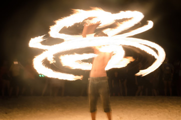 blurry focus a man rotating fireballs on the beach. Night light and have noise