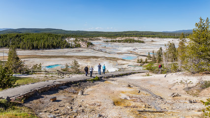 Fototapeta premium The chalky hydrothermal basin circled by a wooden boardwalk. Tourists go on a tour of Porcelain Basin of Norris Geyser Basin, Yellowstone National Park, Wyoming