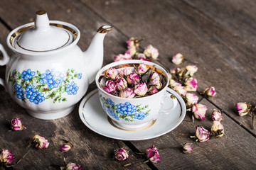 Vintage teapot and cup with blooming tea flowers on wooden background