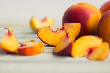 Fototapeta na wymiar Whole peaches and slices, on white wooden board