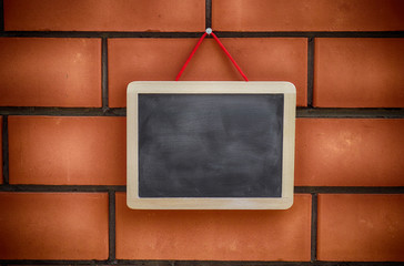 Blank blackboard hanging on a brickwall