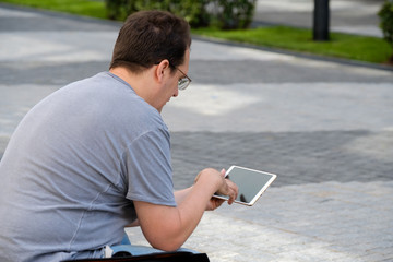 Middle age man reading tablet sitting outdoors