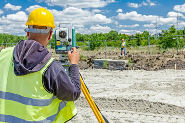 Geodesist is working with total station on a building site. Civi