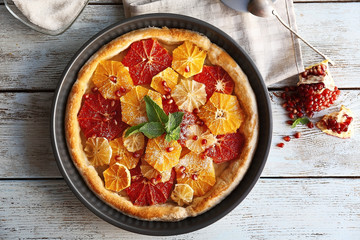 Delicious citrus cake in pan on wooden background