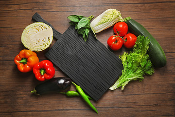 Fresh vegetables and cutting board on wooden background