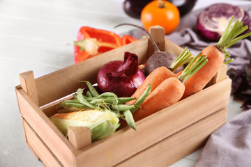 Fresh vegetables in wooden box on light background