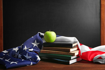 American flag with books and apple on chalk board background