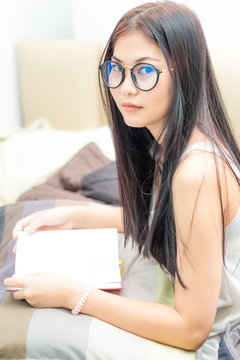Asian nerd woman reading a book and smiling