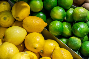 Close up Stack of green lime and yellow lemon on shelf. Fresh yellow and lemons in a box for sale. Yellow and green lemons at a French market.