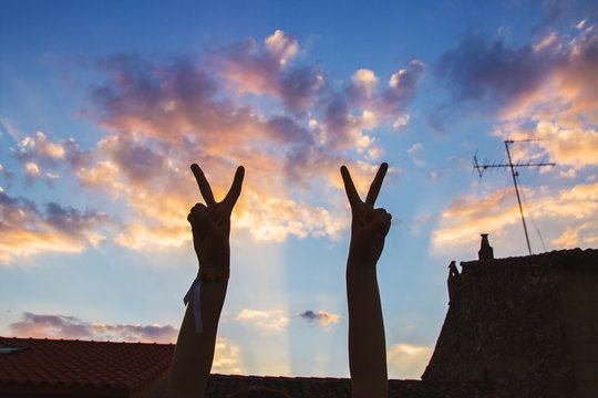 Signos con las manos a contraluz en el cielo 