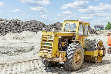 Huge road roller with spikes is compacting soil at construction
