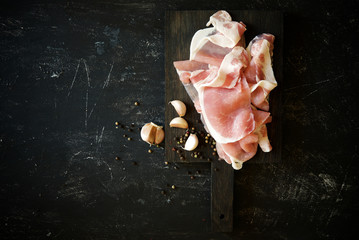 Raw bacon with garlic and spices on a dark background