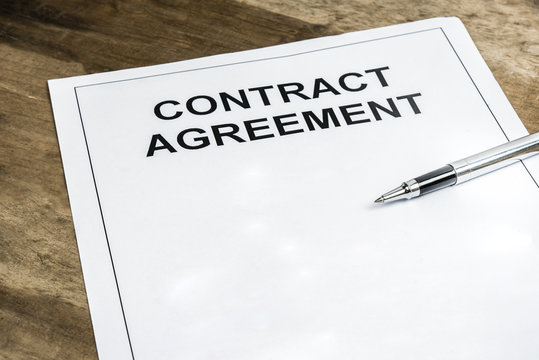 Pen on blank contract agreement paper template on wooden background