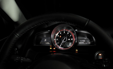 Glowing dial and needle showing zero engine speed in car interior 