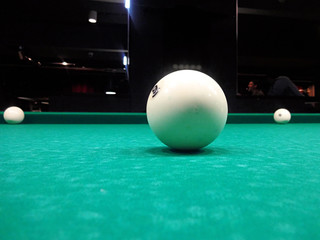 Ivory billiard ball on the green cloth of the table to play