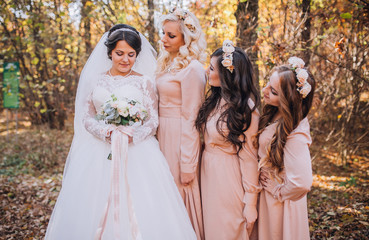 Bride with bridesmaids in a park on the wedding day