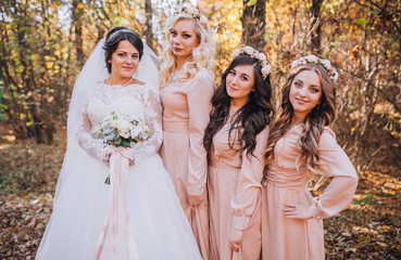 Bride with bridesmaids in a park on the wedding day