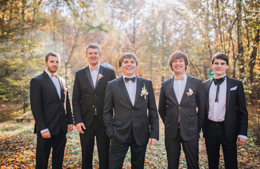 young groom and his funny friends groomsman posing for camera.  Group of young men with bow tie. Cheerful friends. friends outdoors. Wedding day.