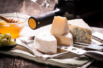 Composition of cheese, berries, bottles and glasses of wine on a wooden table