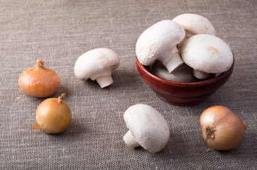 Raw champignon mushrooms and onions on the table