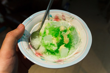 Green shaved ice with jelly on hand.