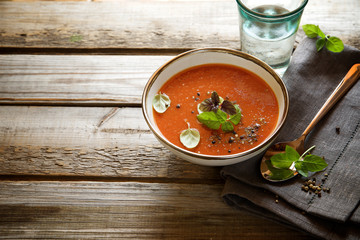 Tomato soup on a wooden table with copy space for an inscription