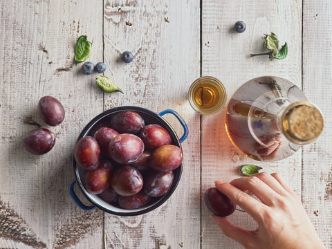 Plum brandy in a glass on a wooden background with fresh plums