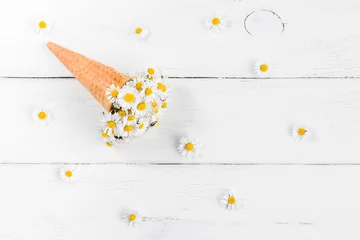 Poster Marguerites daisy flowers in the ice cream cone on white wooden background, flat lay, top view