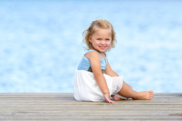 kleines Mädchen sitzt am See
