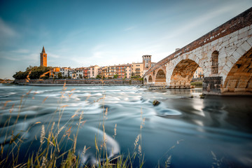 Verona cityscape view on the riverside with historical buildings and Stone bridge on the sunset - obrazy, fototapety, plakaty