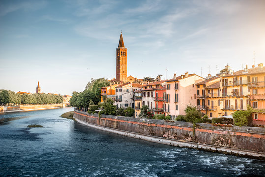 Verona cityscape view on the riverside with historical buildings and tower on the sunset