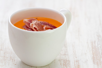 cold soup with smoked meat in white cup on white background