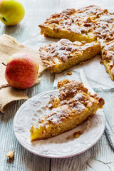Homemade apple and almond cake. Piece of pie on white plate and fresh fruits on wooden background