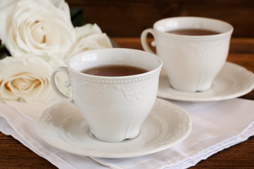 Tea in elegant porcelain cups and flowers