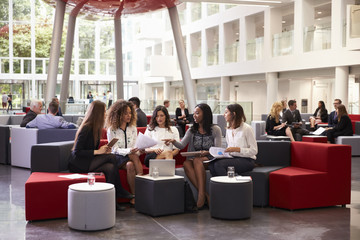 Obraz premium Businesswomen Meeting In Busy Lobby Of Modern Office
