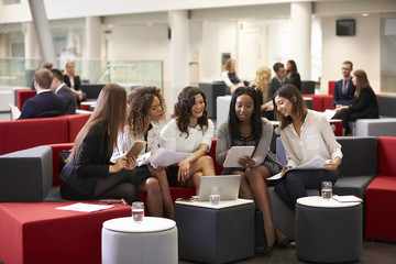 Businesswomen Meeting In Busy Lobby Of Modern Office
