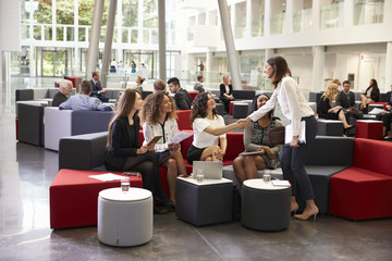 Obraz premium Businesswomen Meeting In Busy Lobby Of Modern Office