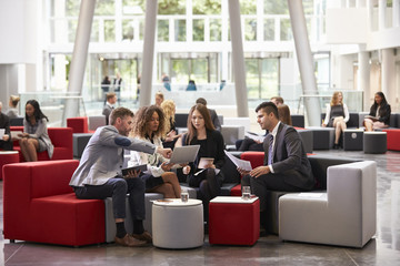 Businesspeople Meeting In Busy Lobby Of Modern Office - obrazy, fototapety, plakaty