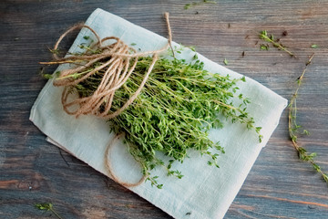 Heap of thyme twigs on linen tissue. Wooden table. Top view, Closeup. Copy space.  - obrazy, fototapety, plakaty