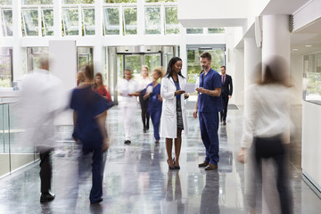 Staff In Busy Lobby Area Of Modern Hospital - Powered by Adobe