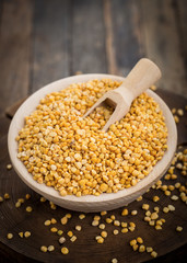 Uncooked yellow lentils in the wooden bowl