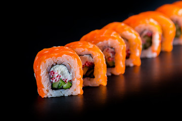 Japanese rolls with fish on a black background