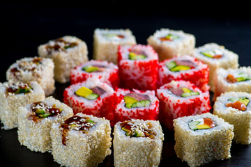 Japanese rolls with fish on a black background