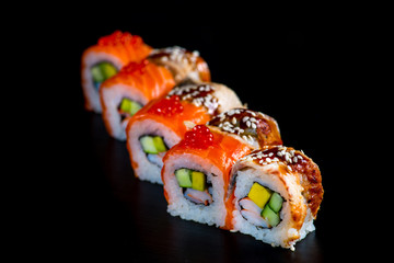 Japanese rolls with fish on a black background
