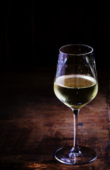 Chilled dry white wine in the glass, vintage wooden background,