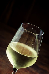 Chilled dry white wine in the glass, vintage wooden background,